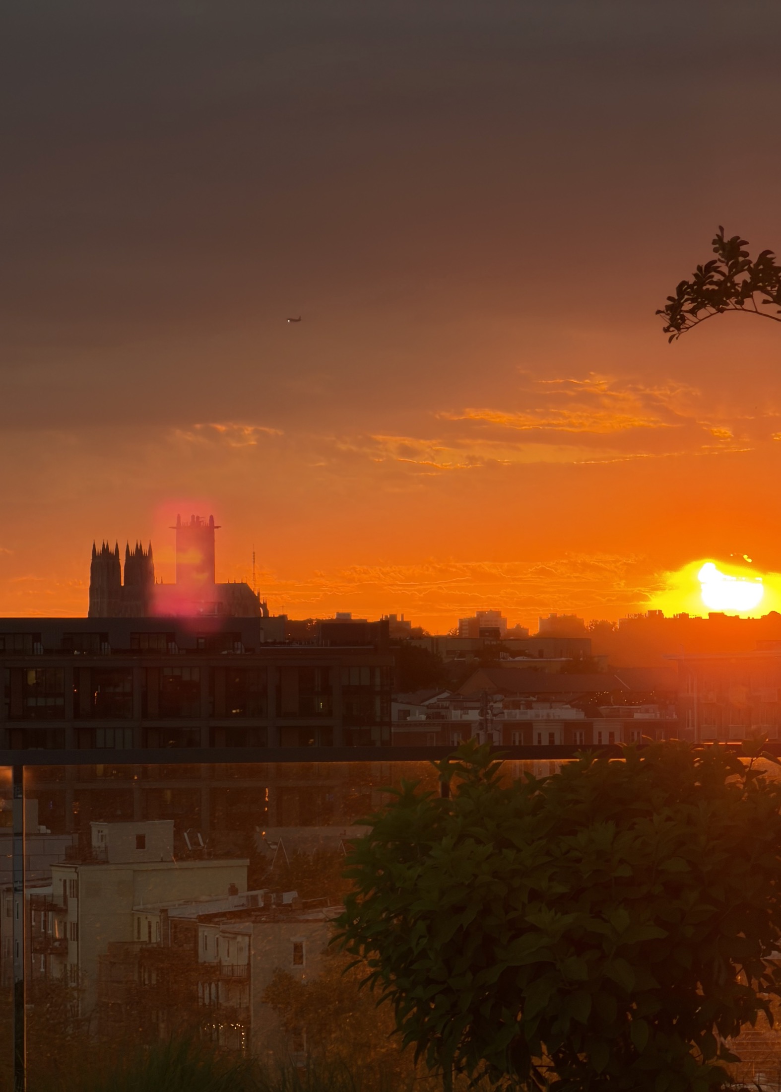 Orange sunset over a cathedral silhouette and city rooftops