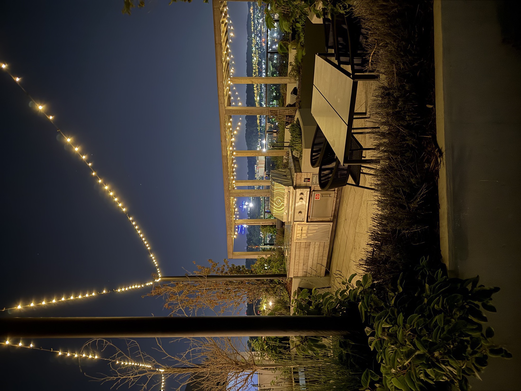Rooftop terrace with string lights over a city at night